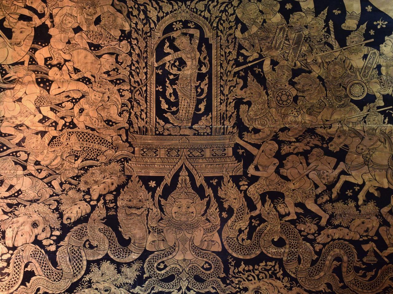 The image depicts a detailed, gold-toned mural with intricate illustrations on a dark background. The mural appears to be of a mythological or religious theme, featuring figures, creatures, and scenes of combat and narrative.